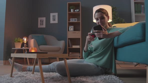 Serene woman chatting with her smartphone at home