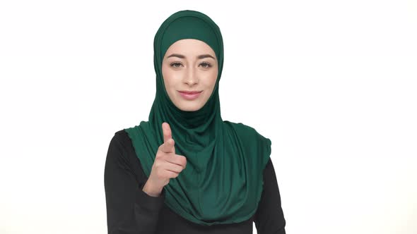 Portrait of Young Religious Woman in Traditional Headscarf Showing Index Finger on Camera Meaning