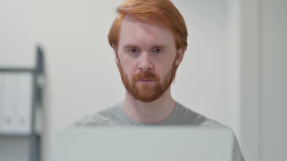 Beard Redhead Man with Laptop Looking at Camera