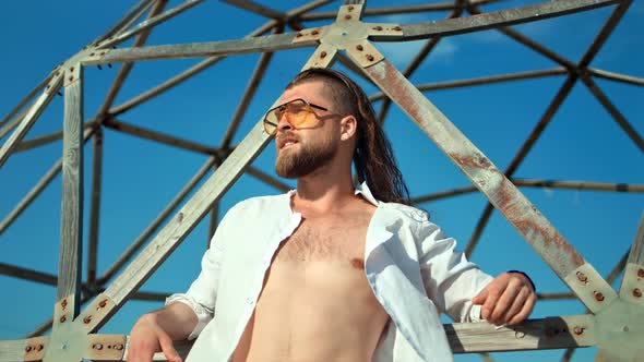 Handsome Male Fashion Model with Naked Torso Posing at Sunny Beach and Sky Background