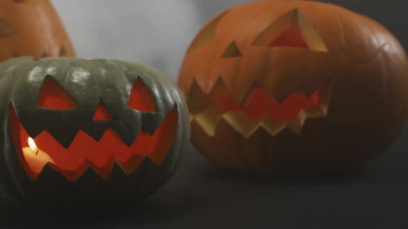 Smoke effect over multiple scary face carved halloween pumpkin against grey background