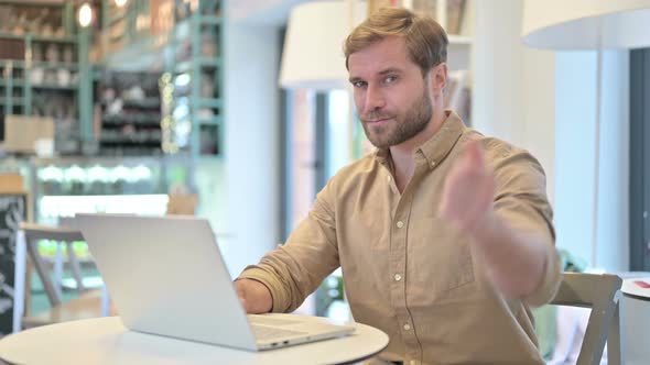 Thumbs Down By Young Man Using Laptop in Cafe