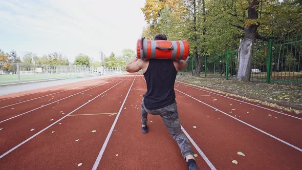 Young man exercising outdoors. Muscular built young athlete working out on stadium