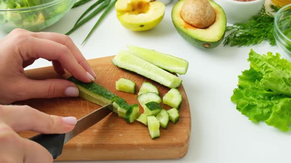 Woman Cooking Salad of Fresh Green Vegetables and Herbs