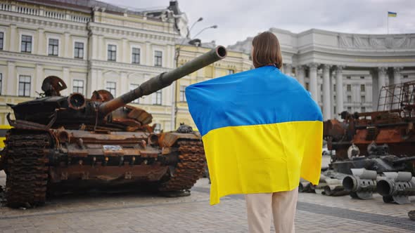 Woman Looks at Tank Turning and Putting Hands in Prayer