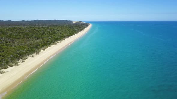 Drone footage of long white sandy beach on a calm sunny day at the Sandy Cape, Fraser Island, Queens