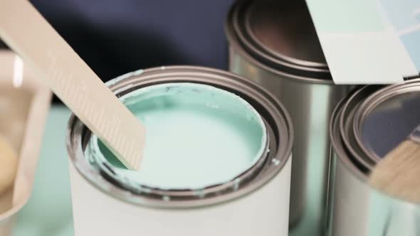 Mixing paint in metal paint can with wooden stick.