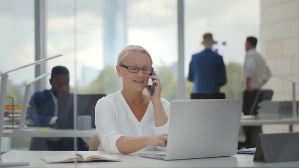 Businesswoman Talking on Mobile Phone Consulting Client Working in Modern Office