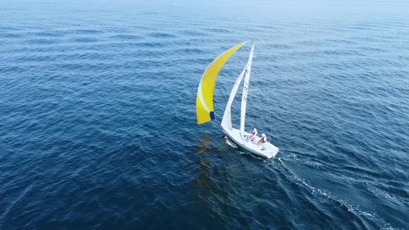 Sea regatta. A beautiful white yacht with a yellow sail sails in the blue sea