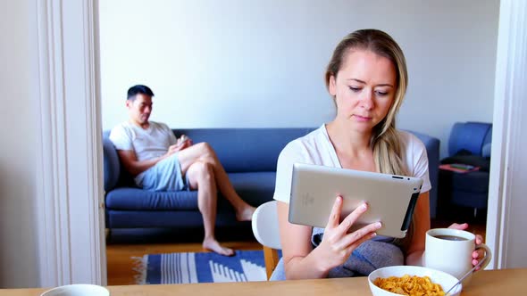 Woman using digital tablet while man using mobile phone