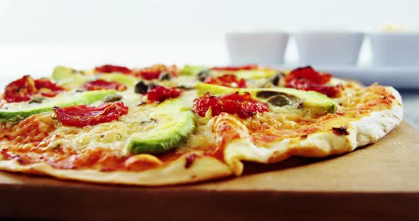 Baked pizza with avocado, cherry tomato and olive toppings