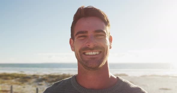 Happy caucasian man standing and smiling by the sea