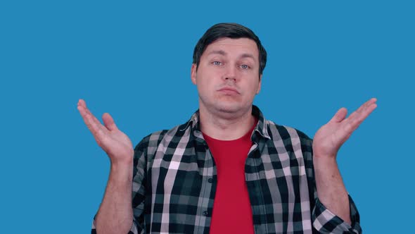 Caucasian man shrugs on blue background.