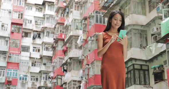 Woman using mobile phone in residential building in Hong Kong city