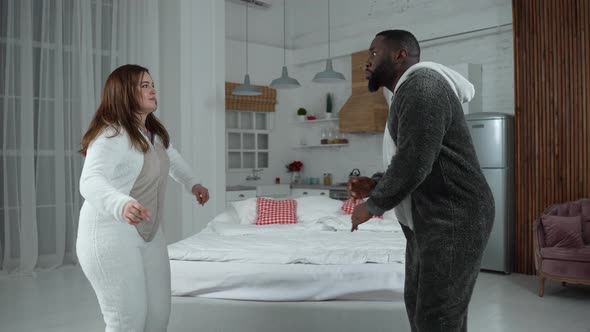 Stylish Couple in Fleece Pajamas Dancing Indoors
