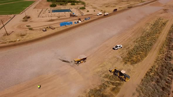 Drone shot of building a dirt wall or border for a rock quarry, spraying rocks on the side of the hi