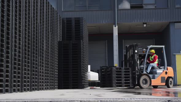 Warehouse worker driving forklift outside factory