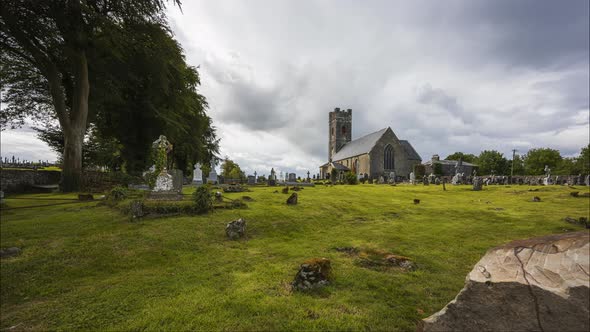 Time lapse of historical cemetery and medieval church in rural Ireland with passing clouds and sunsh