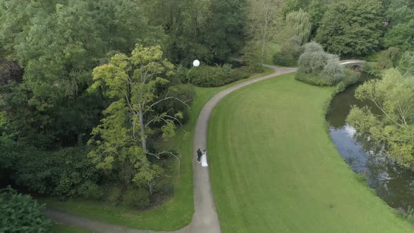 Aerial of Young Millenial Wedding Couple releasing a White Balloon in the Air and Camera Following i