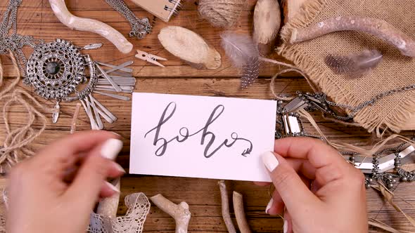 Hand with BOHO handwritten card over a wooden table top view