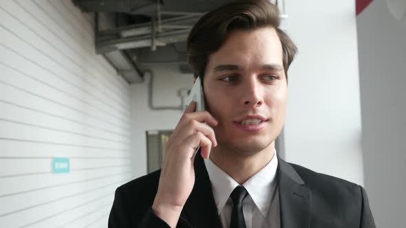 Businessman Walking and Talking on Phone in Office, Close Up