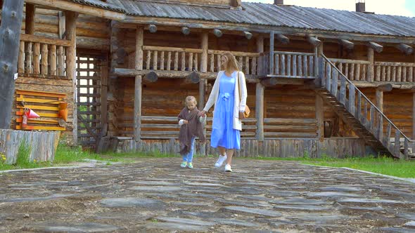 A Woman and Her Daughter are Walking in the Yard of an Old Wooden House