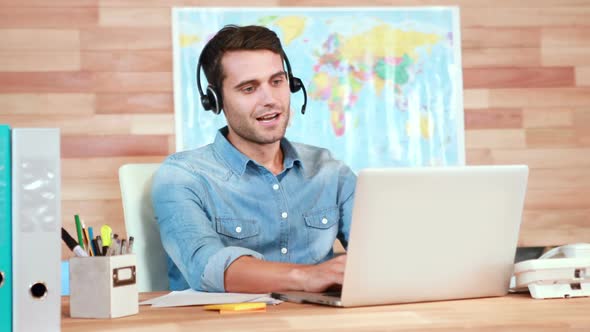 Casual Businessman Using Laptop and Having Conversation with Headset