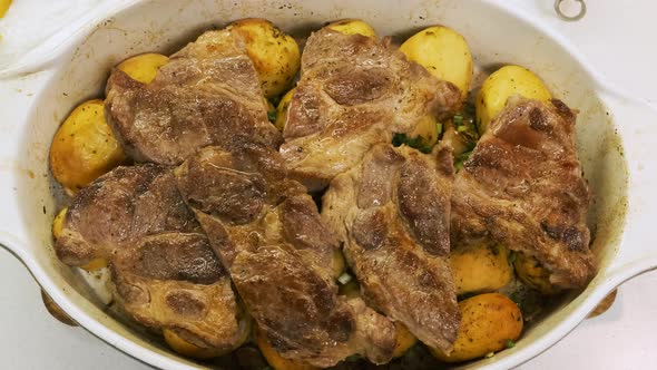 Top View of Juicy Pork Steaks with Potatoes in a Ceramic Dish, Appetizing Meat on the Plate