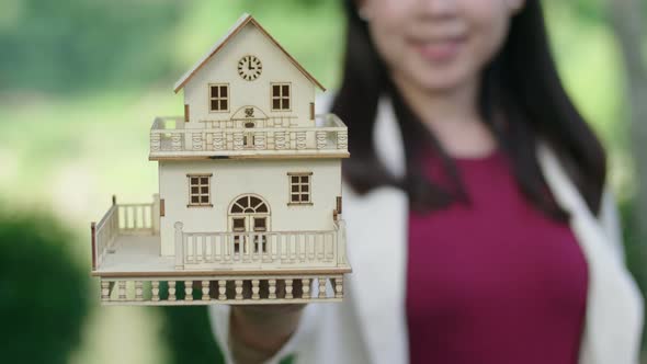 Woman Holding Out In Front Of Her A Small House