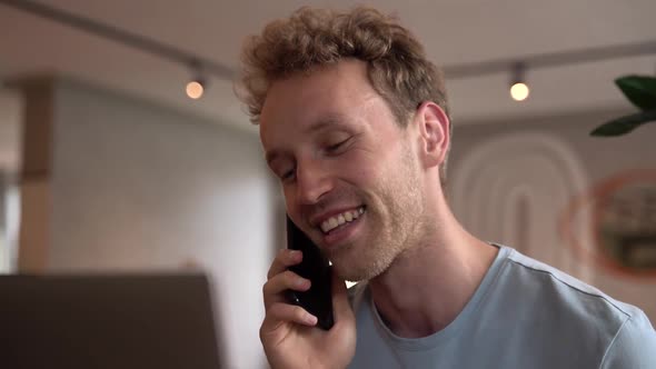 Smiling, positive guy talking on the phone indoors