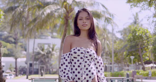 Confident Asian Woman in Dress with Open Shoulder Looking at Camera Folding Hands