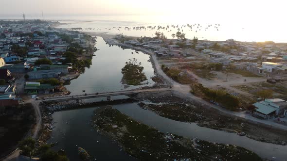 Coastal town on outskirts of Phan Rang with polluted river at sunset. Aerial