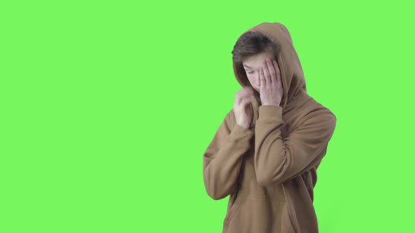 Desperate Caucasian Teenager Rubbing Temples and Sighing. Middle Shot of Sad Boy in Hoodie Posing at