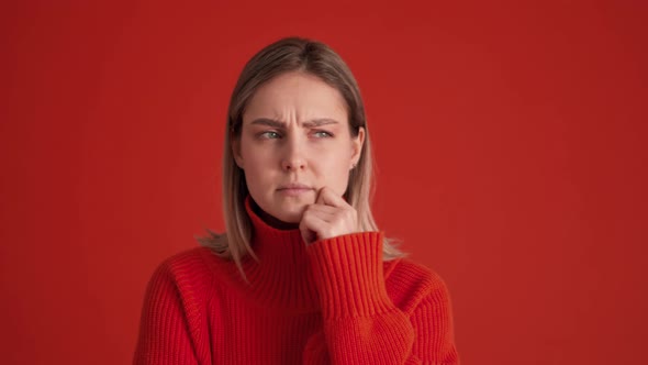 Displeased woman wearing red sweater showing silence gesture at the camera
