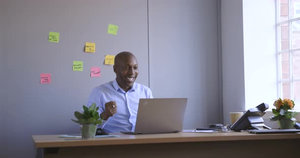 Successful businessman cheering at work in office