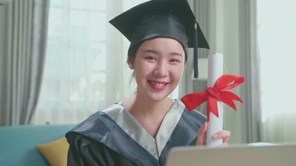 Excited Asian Woman Smiling And Showing Off A University Certificate To Camera