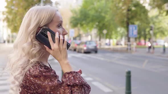 A Middleaged Caucasian Woman Talks on a Smartphone in an Urban Area  Closeup From the Side