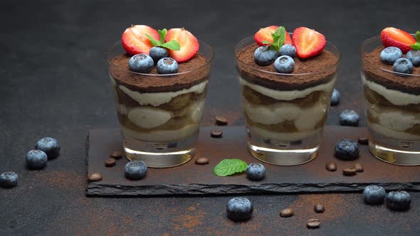 Classic Tiramisu Dessert with Blueberries and Strawberries in a Glass on Stone Serving Board