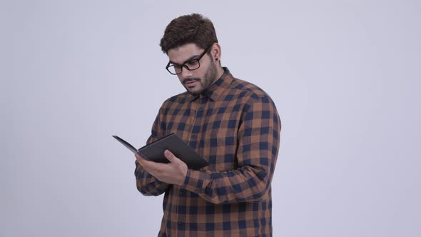 Happy Young Bearded Indian Hipster Man Reading Book