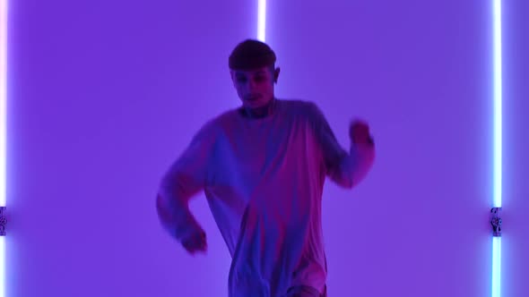 Cool Young Talented Hip Hop Guy Is Dancing Against the Backdrop of Bright Neon Lights Performing