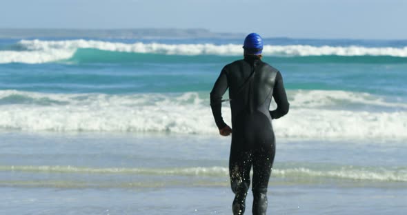 Rear view of male surfer running in the beach