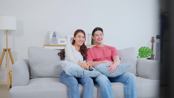 Asian young loving couple watch movie together in living room at home.