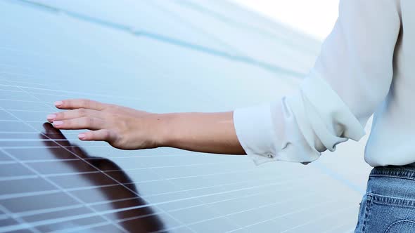 Close up of young woman engineer's hands touching solar panels. Solar energy.