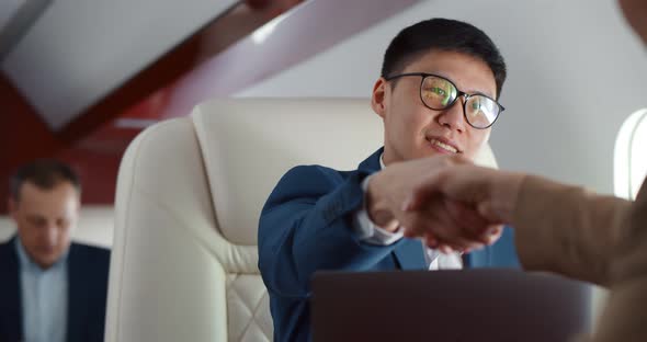 Asian Young Businessman Shaking Hands with Business Partner Flying First Class Together