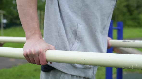 Close-up of the hand of a guy who squeezes out on the uneven bars during workout