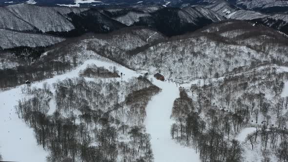 snow capped mountain peaks with skiers in winter at nozawa japan in nagano region, aerial