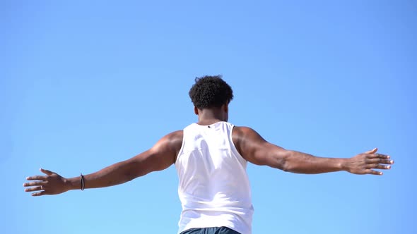 Back View of Man Stretching Arms Against Blue Sky