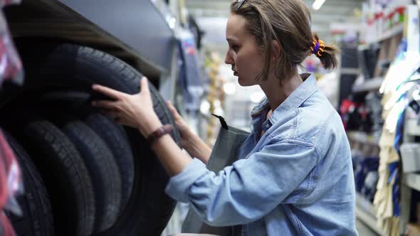 Cute Girl in Big Shopping Center Selecting Car Tyres