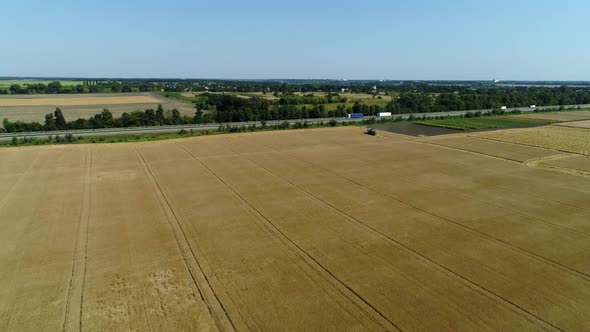 Aerial Drone Footage. Flight Over a Wheat Field with Harvestaer Along the Highway