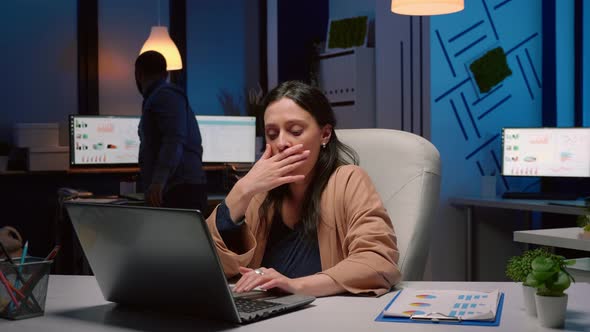 Exhausted Businesswoman Analyzing Marketing Statistics on Laptop Computer